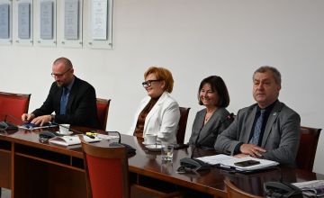 Cztery osoby siedzące przy stole na sali konferencyjnej